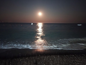 A beach at night with a visible boat on the water.