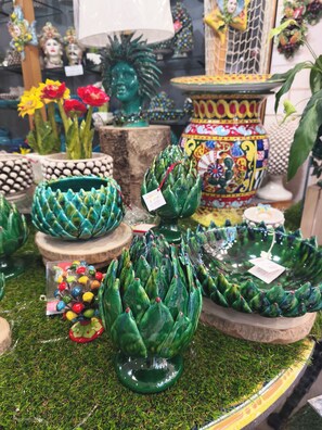 Diversos jarrones y cuencos de cerámica decorativos sobre una superficie cubierta de musgo.