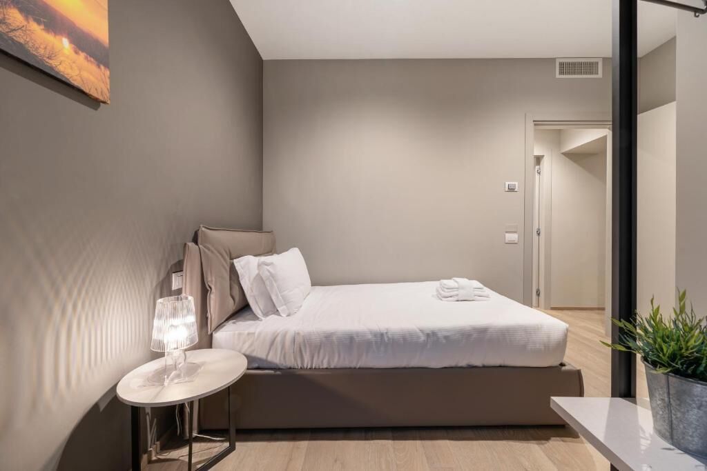 A modern bedroom with a bed, bedside table, and a potted plant.