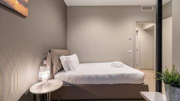 A modern bedroom with a bed, bedside table, and a potted plant.