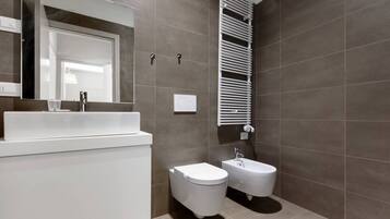 Un baño moderno con un lavabo blanco, un bidé y una bañera.