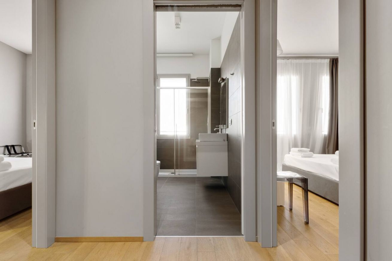 Une chambre d’hôtel moderne avec un plancher en bois, un grand lit, une salle de bain avec douche et une vue sur la ville.