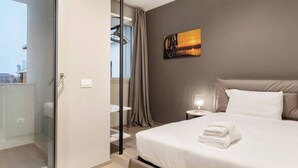 Una habitación de hotel moderna con una cama grande, una puerta de vidrio que da a un balcón y un cuadro en la pared.