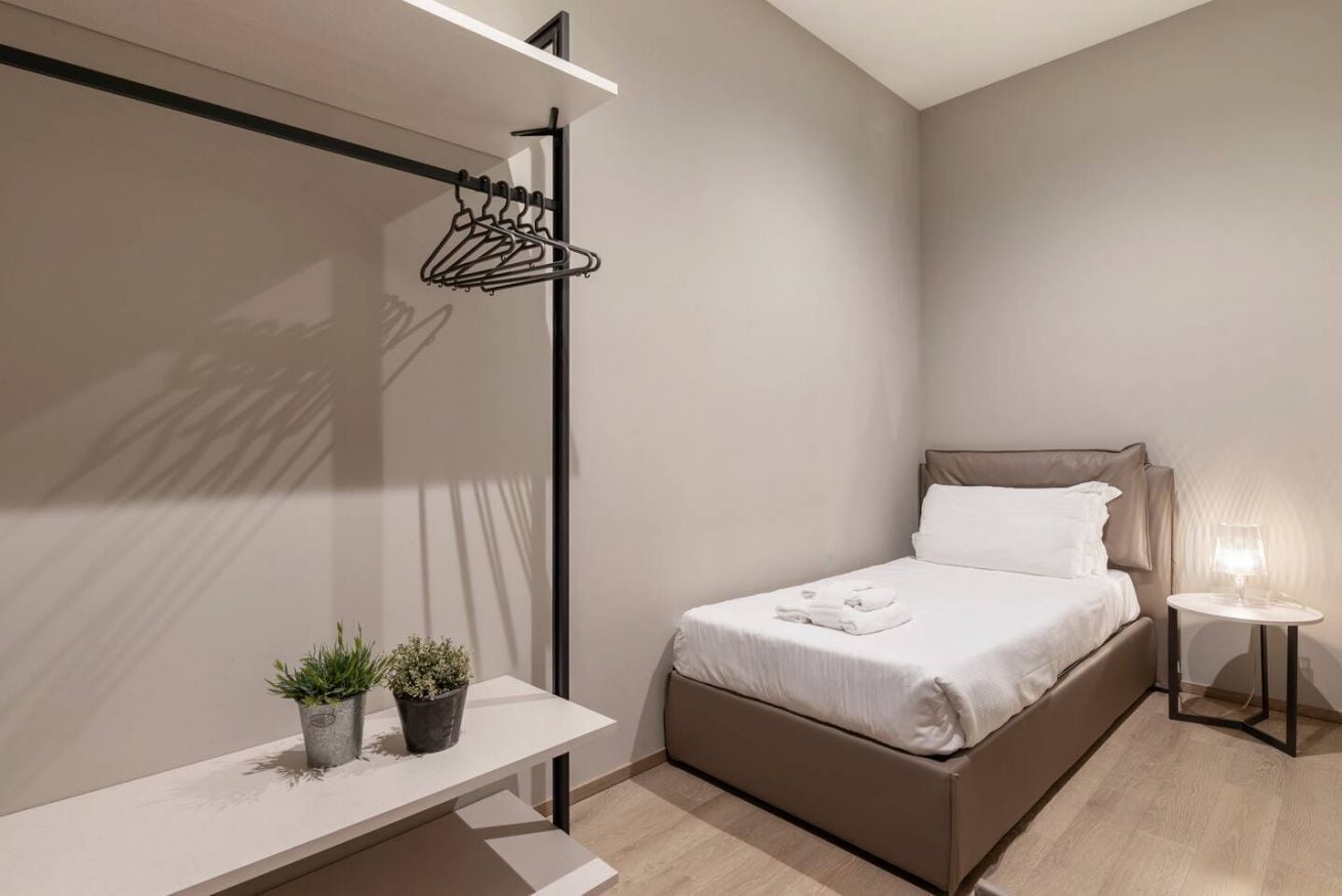 Een moderne slaapkamer met een bed, nachtkastje en kapstok.