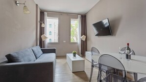 Una sala de estar moderna con un sofá gris, una mesa de centro blanca y una zona de comedor con una mesa y sillas blancas.