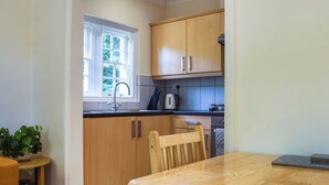 A kitchen with wooden cabinets, a sink, and a window. - 1 bedroom accommodation in Tetsworth, near Oxford (Tetsworth, near Oxford)