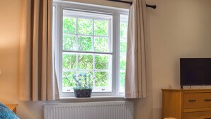 A bedroom with a bed, a dresser, a radiator, a window with curtains, and a potted plant. - 1 bedroom accommodation in Tetsworth, near Oxford (Tetsworth, near Oxford)