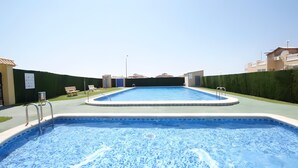 A rectangular swimming pool with a clear blue water surface, surrounded by a low concrete deck. - Apartment 'Jardin Del Mar Paraje Natural' with Lake View, Shared Pool and Air Conditioning (Torrevieja)