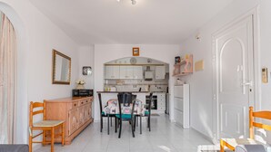 A modern kitchen with white cabinets, a dining table with chairs, and a small island. - Apartment 'Jardin Del Mar Paraje Natural' with Lake View, Shared Pool and Air Conditioning (Torrevieja)