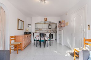 A modern kitchen with white cabinets, a dining table with chairs, and a small island.