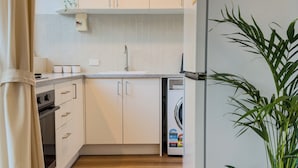 Uma cozinha moderna com armários brancos, forno embutido, micro-ondas e lava-louças.