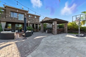 A patio area with outdoor seating, a pergola, and a basketball hoop.