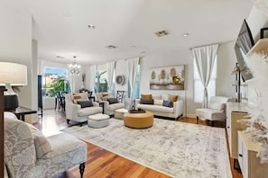 A spacious living room with a large sofa, ottoman, and a dining area in the background.