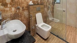 Een moderne badkamer met een glazen douchecabine, een wastafel met een marmeren blad en een toilet met een houten opbergmeubel.