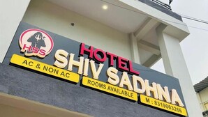 Een hotelschbord met de naam 'HOTEL SHIV SADHNA' en een logo dat 'Airconditioning & zonder Airconditioning' kamers aangeeft.