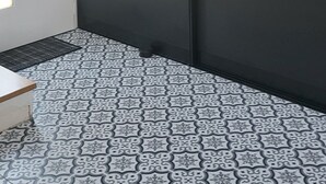 Una habitación con techo inclinado, piso estampado, puerta corredera y un ventanal pequeño.
