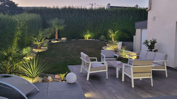 Un patio con mobiliario exterior, un césped bien cuidado y un seto al fondo.