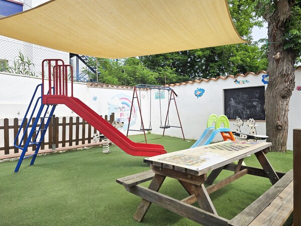 A playground with a slide, swings, and a picnic table.