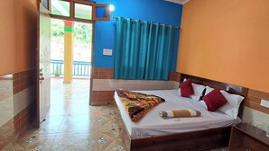 A hotel room with a bed, a wooden headboard, a window with blue curtains, and a view of the outside. - Hotel Mountain Paradise Barkot (Barkot)