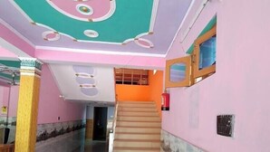 A multi-level interior with a staircase, a reception desk, and a mural on the lower wall. - Hotel Mountain Paradise Barkot (Barkot)