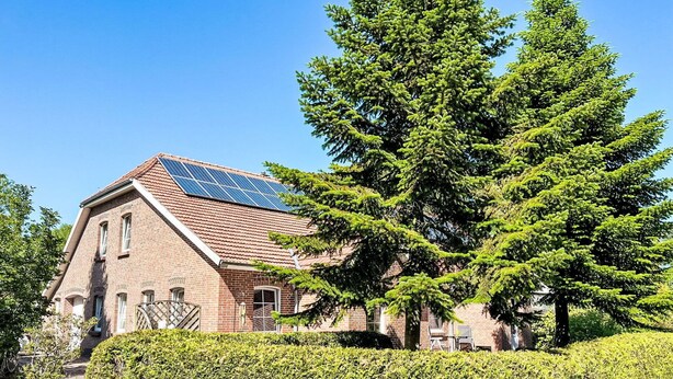 A brick building with a sloped roof and solar panels.