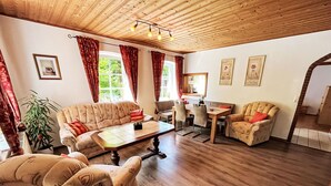 A cozy living room with a sofa, armchairs, a coffee table, and a dining area with chairs and a table.