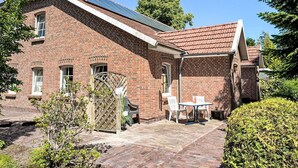 A brick building with a sloped roof, solar panels, a wooden gate, and a patio with outdoor furniture.