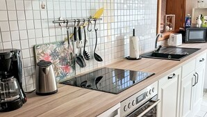 A kitchen with white cabinets, a Bosch dishwasher, a microwave, and a coffee maker.