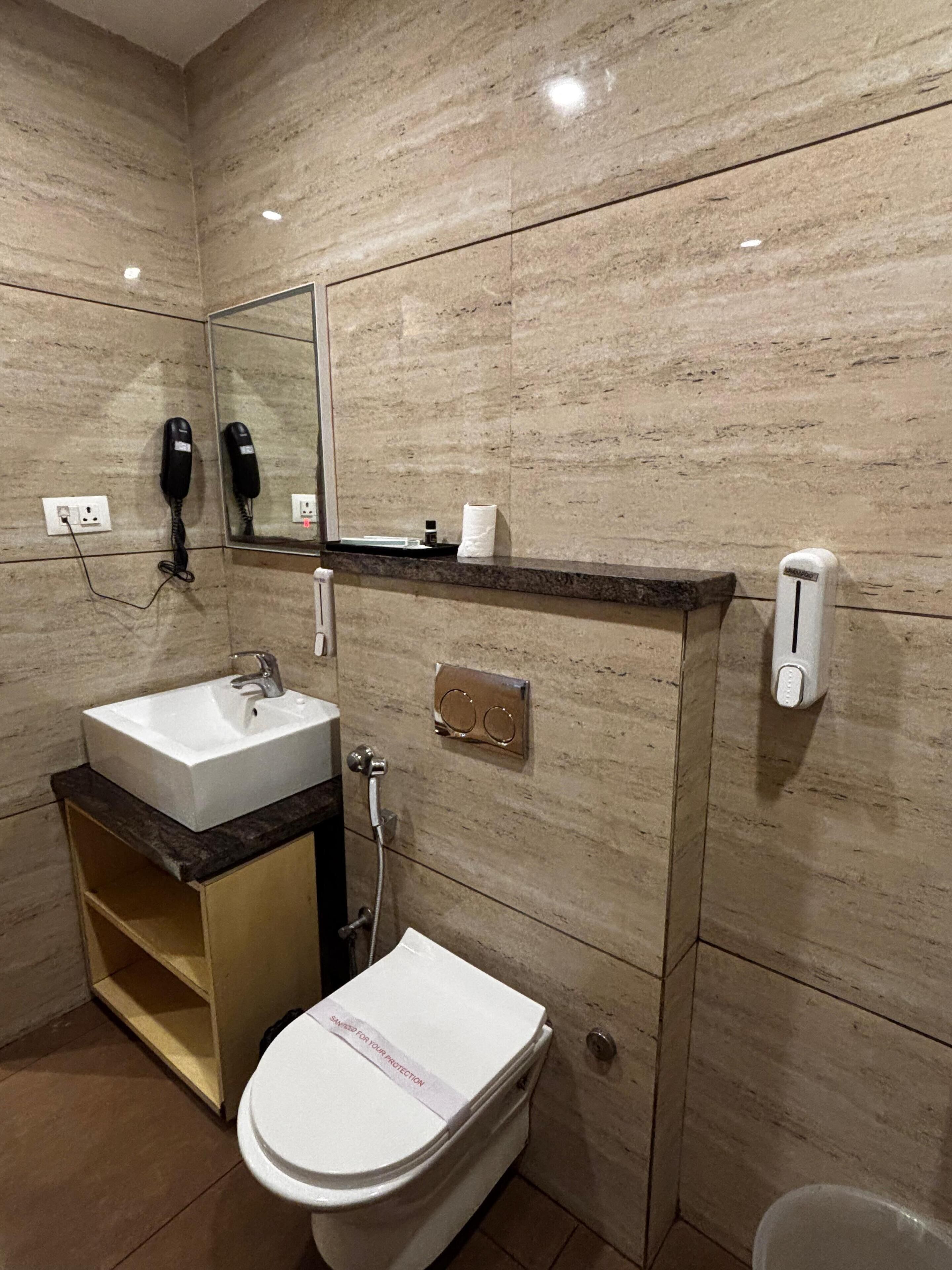 A modern bathroom with a white sink, a toilet, and a mirror above the sink.