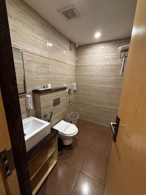 A compact bathroom with a sink, toilet, and mirror. - Hotel Bastion (Bhopal)