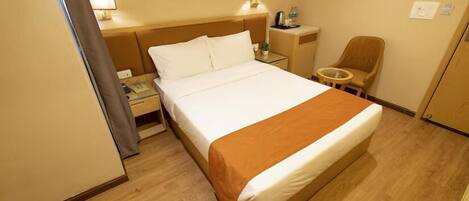 Quarto de hotel com cama, mesa de cabeceira, cadeira e um quadro na parede.