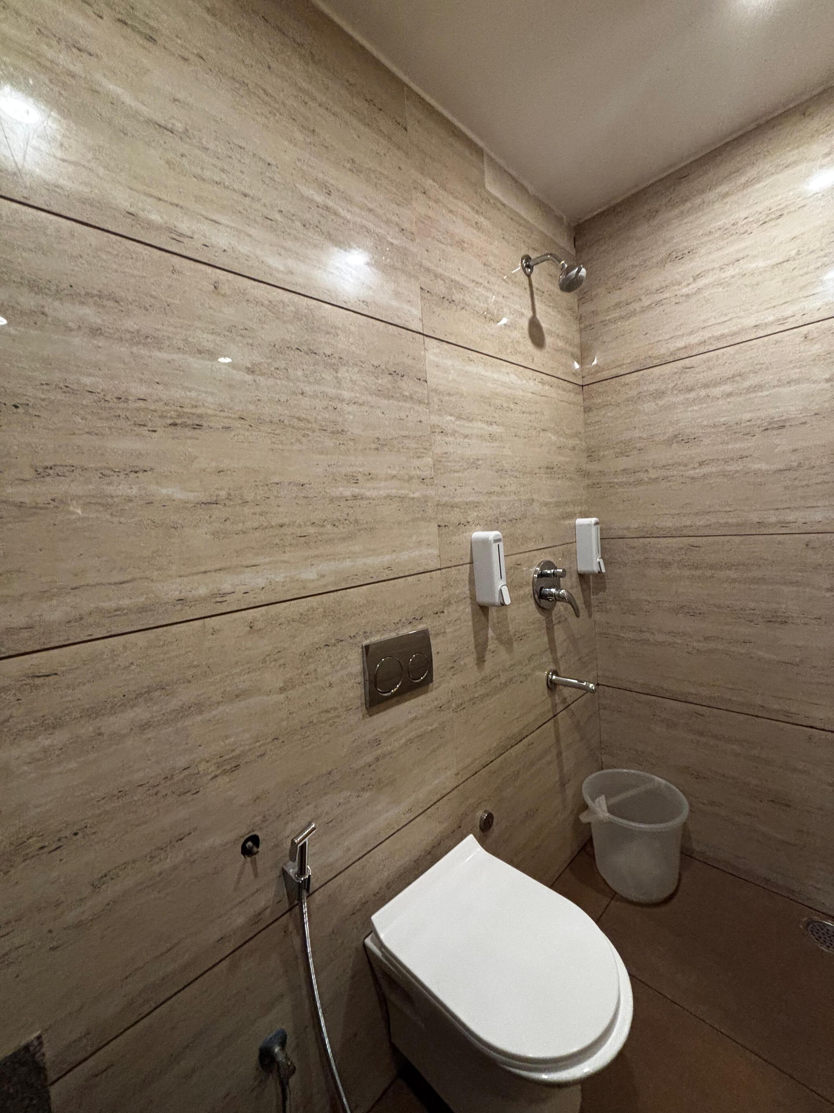 Ein Badezimmer mit Toilette, Dusche und einem Händetrockner.