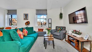 A modern living room with a green sofa, a grey armchair, a coffee table, and a TV mounted on the wall. - Wonderful  villa for 3 people with WIFI and pets allowed (Ripon)