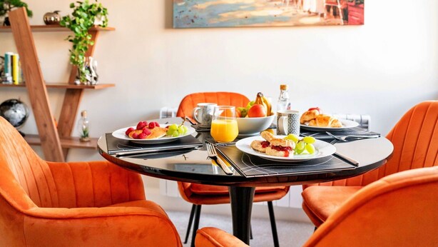 A dining table with orange chairs, plates of food, and a glass of orange juice. - Wonderful  villa for 3 people with WIFI and pets allowed (Ripon)