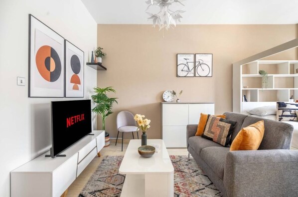 A modern living room with a flat-screen TV, a sofa, a coffee table, and a bookshelf. - Luxurious Studio In Dubai (Arjan)