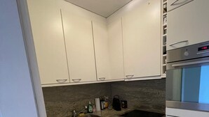 A kitchen with white cabinets, a stainless steel sink, a built-in oven, and a dishwasher. - Vacation apartment Brissago (Brissago)