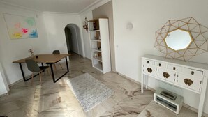 A dining area with a wooden table and chairs, a white console with drawers, and a geometric wall decoration. - Vacation apartment Brissago (Brissago)