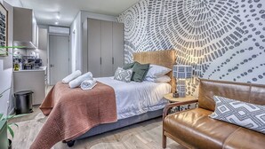 Un dormitorio moderno con cama, mesita de noche y un sofá de cuero marrón.