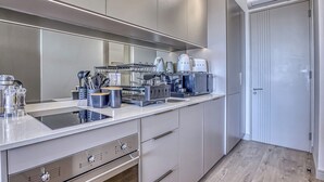 Una cocina moderna con electrodomésticos de acero inoxidable, horno empotrado y una encimera amplia.