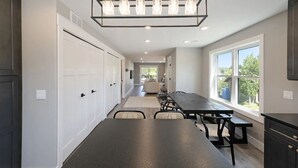 Una cocina moderna con una isla grande, iluminación colgante y vistas al exterior.