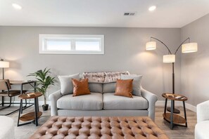 A modern living room with a grey sofa, two brown leather armchairs, a round coffee table, and a floor lamp.