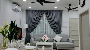 Un salon moderne avec un canapé gris, deux ventilateurs de plafond et un coin repas avec une table dressée pour quatre personnes.