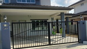 Une maison à deux étages avec une allée couverte et une entrée fermée par un portail.