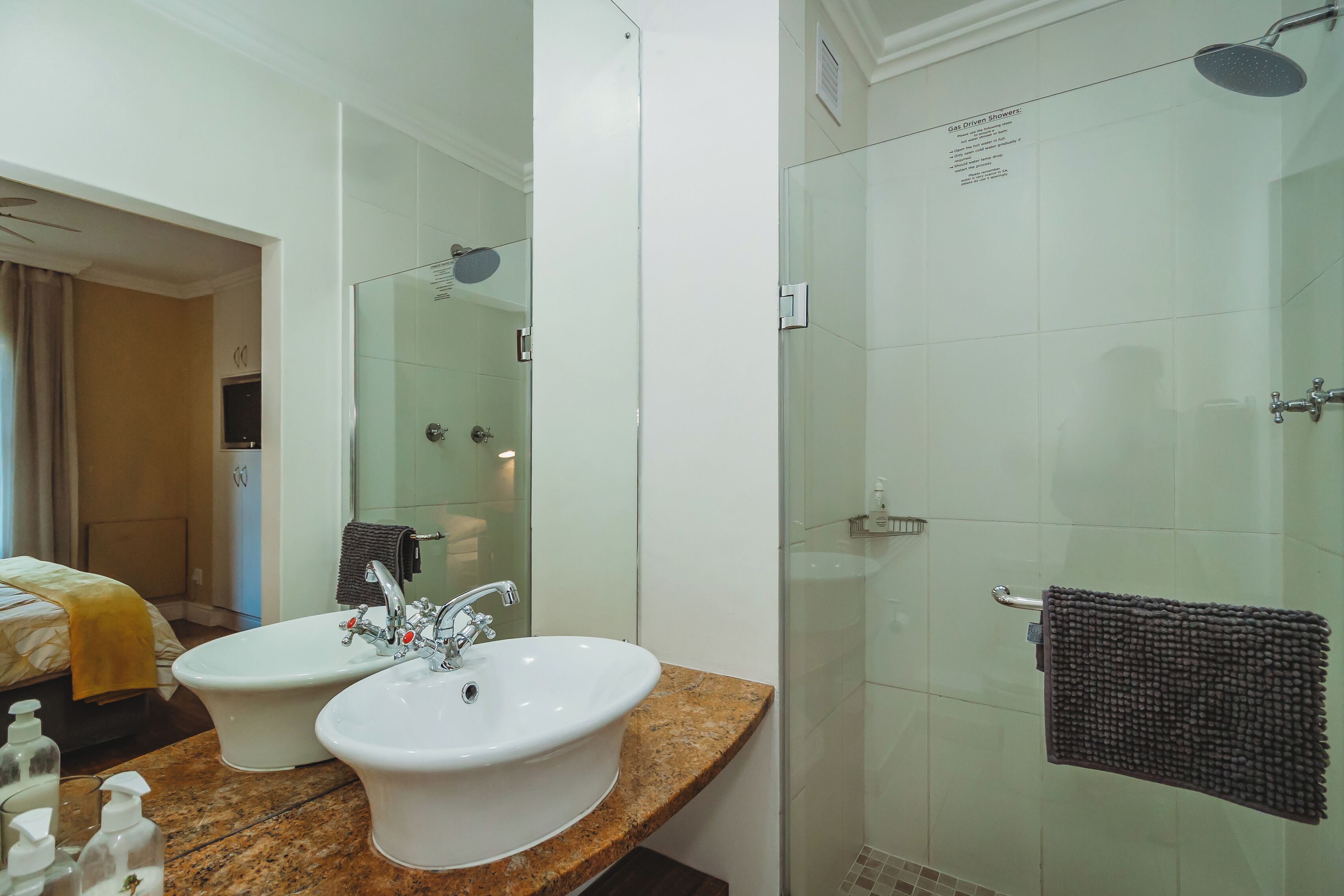 A bathroom with two sinks, a shower, and a mirror.