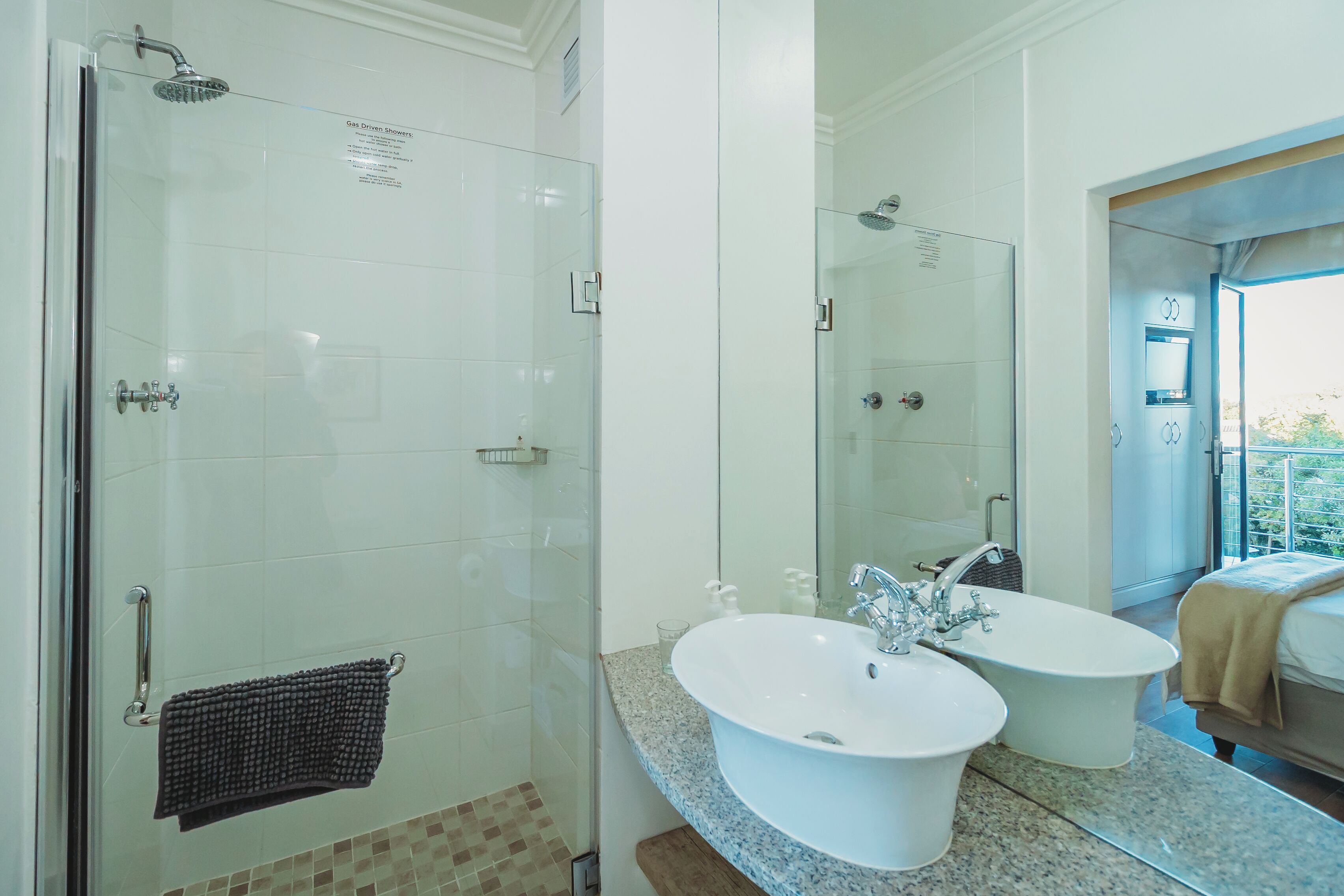 A modern bathroom with a glass-enclosed shower, a double sink vanity, and a large mirror.