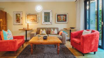 A living room with a sofa, two armchairs, a coffee table, and a side table. There are three framed pictures on the wall.