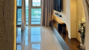 Ein modernes Interieur mit einem großen Fenster, einem Wand-Fernseher und einer Zimmerpflanze auf einer Konsolentisch.