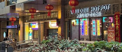 Un edificio comercial de varios niveles con diversas tiendas, incluyendo Starbucks y un restaurante llamado “WOW COW HOT POT”.