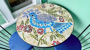 Ein runder Tisch mit Mosaikmuster, umgeben von blauen Sitzstühlen mit Polstern.