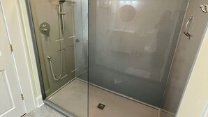 Ein modernes Badezimmer mit einer Duschkabine aus Glas, einem Waschbecken und einem Spiegel.